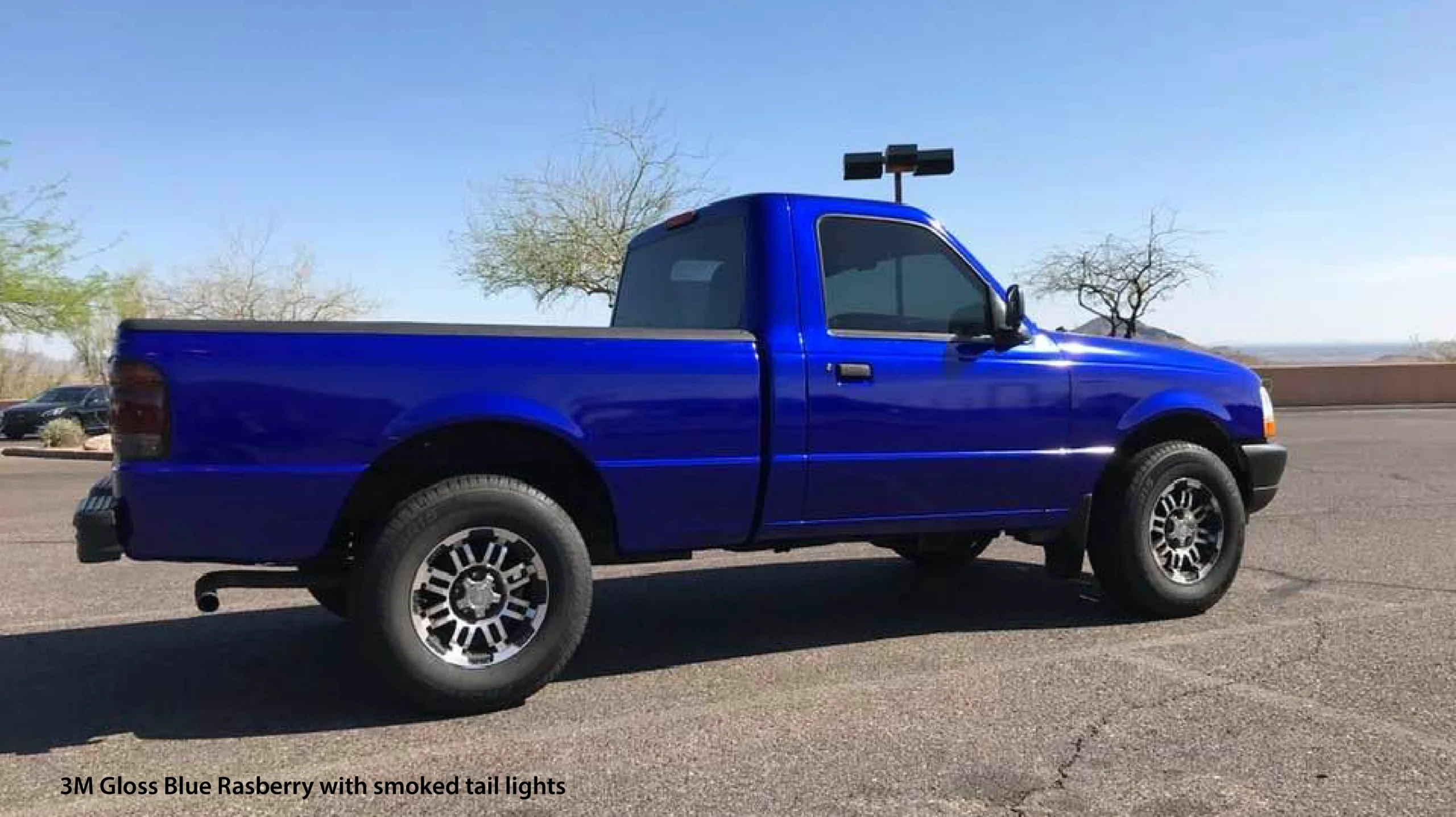 Blue pickup truck with off-road modifications and camera mount on roof.